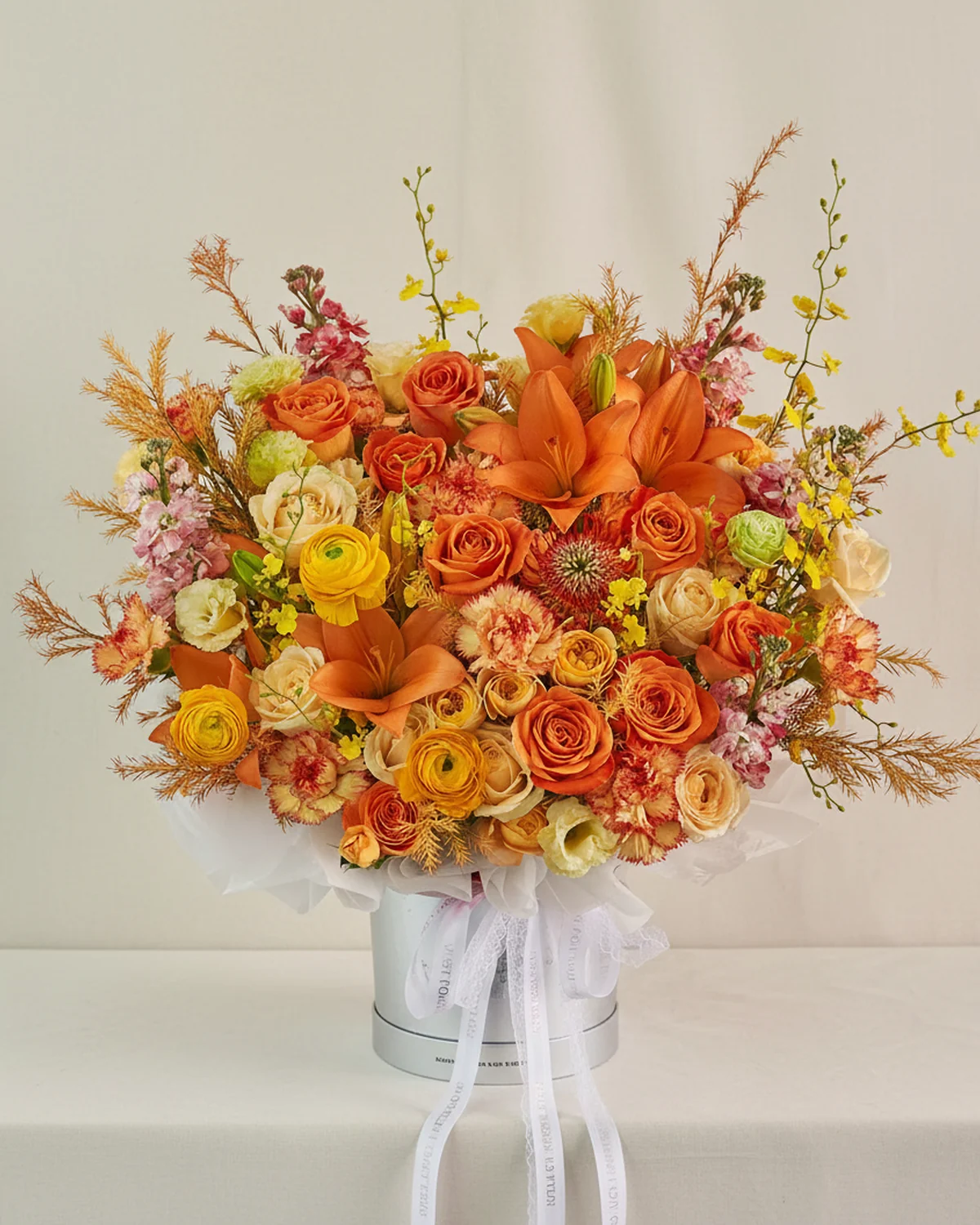 Overflowing Orange Flower Bucket — Orange lilies — 2 stems (4 heads/stem), Orange roses — 10 stems, Yellow ranunculus — 3 stems, Champagne roses — 8 stems, Champagne eustoma — 4 stems (3 heads/stem), Red pincushion chrysanthemum, Orange carnations — 9 stems, Yellow dancing orchids — 4 stems, White stock flowers — 5 stems (sprayed red), Orange multi-head roses — 4 stems (4 heads/stem), Golden solidago — 12 stems, 19.5cm large flower bucket — 1 unit