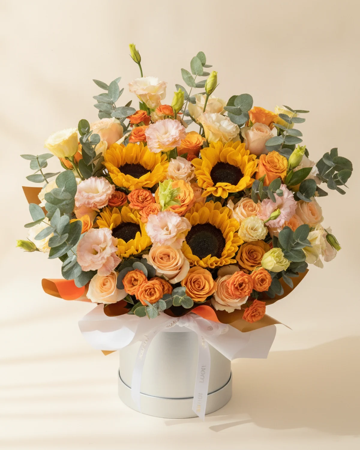 Golden Embrace Large Flower Bucket — Sunflowers — 4 stems, Champagne roses — 12 stems, Brilliant roses — 8 stems, Orange multi-head 'bubble' roses — 4 stems (6+ heads/stem), Champagne-coloured multi-head eustoma — 5 stems, Eucalyptus foliage, 19.5cm large flower bucket — 1 unit